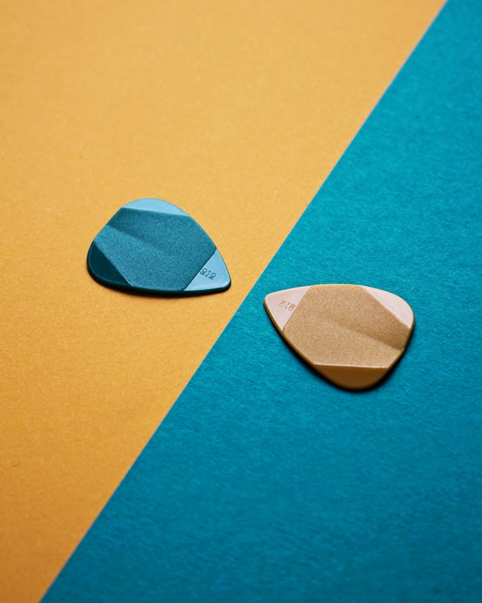 Bright, colorful guitar picks displayed on contrasting yellow and blue background for a modern, artistic feel.