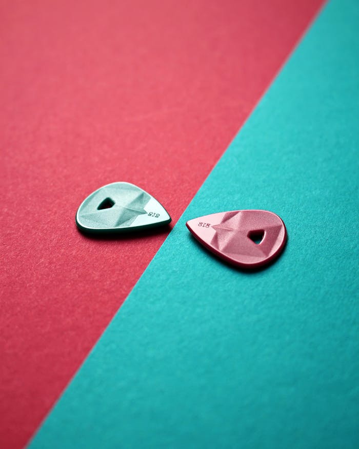 Two colorful guitar picks on a green and pink background, creative still life.